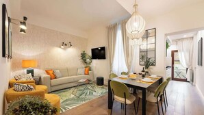 A modern living room with a sofa, dining table, and chairs, a flat-screen TV, and a large window with curtains. - Guelfa Spacious New Elegant Central Position (Firenze)