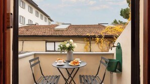 A balcony with a table and chairs, a potted plant, and a green outdoor grill. - Guelfa Spacious New Elegant Central Position (Firenze)