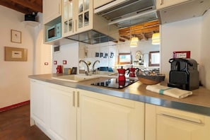 Eine moderne Küche mit weißen Schränken, einer Edelstahl-Spüle, einer Kaffeemaschine und einem Toaster.
