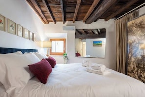 Ein Hotelzimmer mit Bett, Kissen, einem Spiegel und Bildern an der Wand.