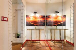 A hallway with a glass partition, a red-framed mirror, a glass table, and a cityscape painting. - CS Giorgio Hidden Gem Close to Ponte Vecchio (Firenze)