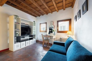 A living room with a TV, a desk, a chair, a sofa, and a bookshelf. - CS Giorgio Hidden Gem Close to Ponte Vecchio (Firenze)