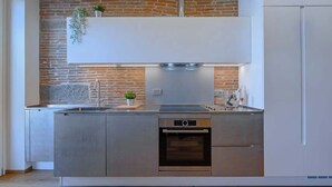 Een moderne keuken met een bakstenen muur, roestvrijstalen apparatuur en een wit bovenkastje.