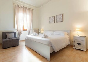 Ein Schlafzimmer mit Bett, Nachttisch, Sessel und Beistelltisch.