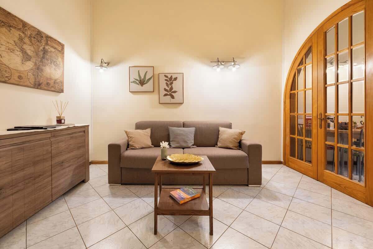 A living room with a sofa, a coffee table, a cabinet, wall art, and a wooden door.