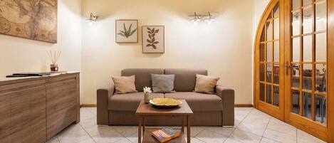 Una sala de estar con sofá, mesa de centro, aparador, decoración en la pared y una puerta de madera.