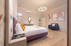A hotel room with a bed, a desk, a chair, a sofa, a chandelier, and artwork on the walls. - Reparata Wide Beautiful 10 min to Train Station (Firenze)