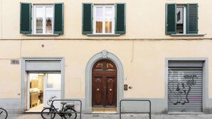 Ein Gebäude mit einer Holztür, einem davor abstellenden Fahrrad und einer Garage mit Graffiti.