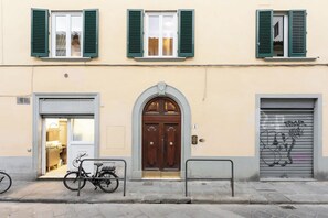 A building with a wooden door, a bicycle parked in front, and a garage door with graffiti. - Reparata Wide Beautiful 10 min to Train Station (Firenze)