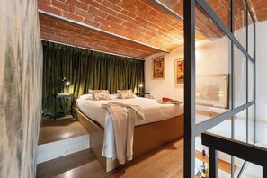 A modern hotel room with a large bed, a brick ceiling, and a view through a glass door. - Cimabue Design Loft in a Cool Area of Florence (Firenze)