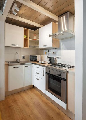 A modern kitchen with white cabinets, a stainless steel stove, and a microwave. - Cimabue Design Loft in a Cool Area of Florence (Firenze)