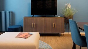 Una sala de estar moderna con un televisor de pantalla plana, una pared de acento azul, un mueble de madera y una alfombra redonda.