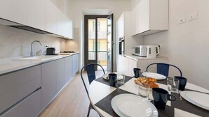 Una cocina moderna con comedor, que incluye una mesa preparada para el desayuno con cruasanes y café.