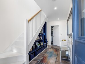 A modern hallway with a staircase, a blue storage unit, and a patterned rug. - Brentwood/Luxury Ocean View Retreat in Connemara (Renvyle, Connemara)