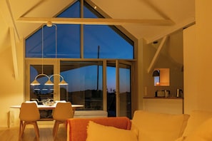 Ein modernes Interieur mit Essbereich, einer Couch und einem großen Fenster mit Aussicht.