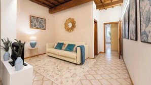 A living room with a sofa, a coffee table, a lamp, and a decorative mirror. - Egidio Spacious and bright 300mt from the Duomo (Firenze)
