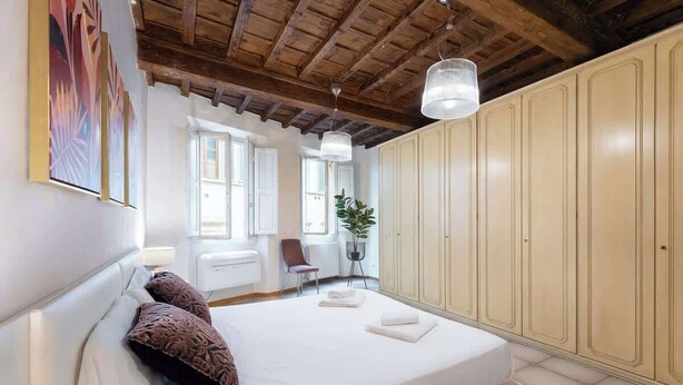 A bedroom with a large bed, a wooden ceiling, and a wardrobe. - Egidio Spacious and bright 300mt from the Duomo (Firenze)