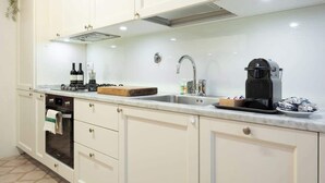 A kitchen with white cabinets, a built-in oven, a coffee maker, and a sink. - Egidio Spacious and bright 300mt from the Duomo (Firenze)