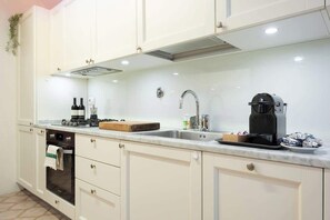 A kitchen with white cabinets, a built-in oven, a coffee maker, and a sink. - Egidio Spacious and bright 300mt from the Duomo (Firenze)
