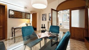 A modern living room with a glass table, blue chairs, a hanging light fixture, and a view of the street. - Egidio Spacious and bright 300mt from the Duomo (Firenze)