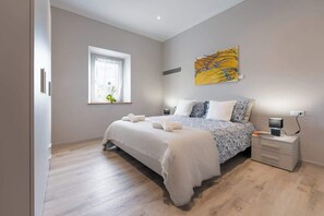 Ein Schlafzimmer mit Bett, Nachttischen, einem Fenster und einem Bild an der Wand.