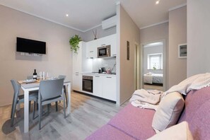 Eine moderne Wohnung mit Essbereich, Küchenzeile und Wohnzimmer mit Sofa.