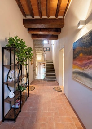 Ein Flur mit einer Treppe, einem schwarzen Metallregal mit Pflanzen und einem Gemälde an der Wand.