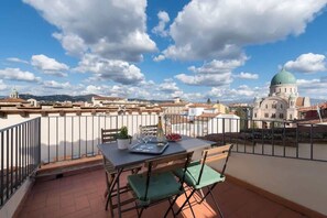 Ein Balkon mit Tisch für zwei Personen, einem Topfpflanzen und einer Champagnerflasche.