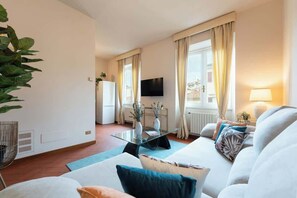 Ein modernes Wohnzimmer mit einer Couch, einem Glastisch und einem an der Wand montierten Fernseher.