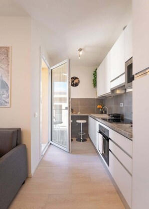 Une cuisine moderne avec des armoires blanches, une hotte de cuisinière en acier inoxydable et un plan de travail noir.