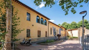 Ein Gebäude mit gelber Fassade, Rundbogenfenstern und einem gepflasterten Innenhof.