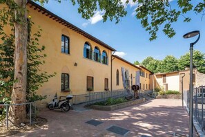 A building with a yellow facade, arched windows, and a paved courtyard. - Giano - Conventino Modern - Apt con Garage (Firenze)