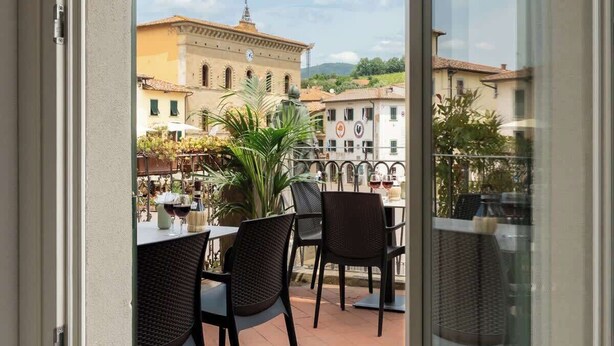 Eine Terrasse mit Außenbestuhlung, Blick auf ein historisches Gebäude und einen klaren Himmel.