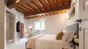 Ein Schlafzimmer mit Bett, Fenster, Heizkörper und einer Tür zu einem Badezimmer.