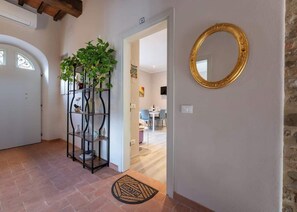 A hallway with a plant shelf, a mirror, and a welcome mat. - Civette 1, Studio Apt with Shared Garden View (Greve in Chianti)