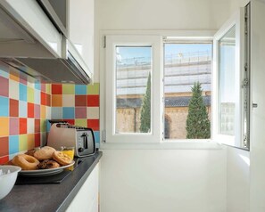 Eine Küche mit einem Toaster, einer Platte Gebäck und einem Fenster mit Blick auf Gebäude und Bäume.