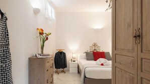 Un dormitori amb un llit, un armari, una taula de nit, una commode i un penjador.