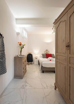 Ein Schlafzimmer mit Bett, Kleiderschrank, Nachttisch, Kommode und einer Garderobe.