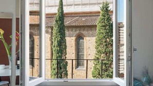 Balcó obert amb vista a un edifici històric i dues alzines altes.