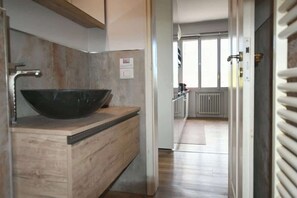 A modern kitchen with a large black bowl sink, wooden countertop, and a view of the living area through an open door. - Bright Florence Apt: Near Center+Fast WiFi+Balcony (Firenze)