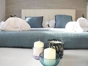 Un dormitorio con una cama, almohadas y tres velas delante.