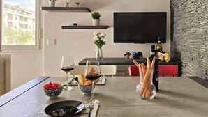 Ein moderner Essbereich mit einem Tisch für zwei Personen, einem an der Wand montierten Fernseher und einer Wand mit Steinoptik.