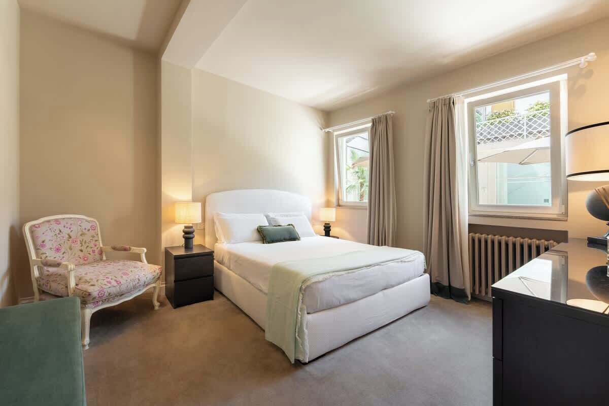 Ein Hotelzimmer mit Bett, Stuhl, Schreibtisch und einem Fenster mit Vorhängen.