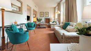 Una sala de estar con un sofá, dos sillones, una mesa de centro, una chimenea y un espejo.