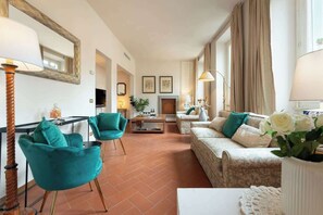 A living room with a sofa, two chairs, a coffee table, a fireplace, and a mirror. - Antonella Elegant 3-Bedroom in Prime Location (Firenze)