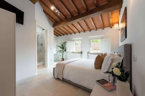 A bedroom with a large bed, a potted plant, a window, and a door leading to a bathroom. - Casa Falorni, 4 - Cassero - Bilocale (Greve in Chianti)