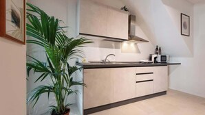 Una cocina moderna con un lavamanos, armarios, un microondas y una planta en maceta.
