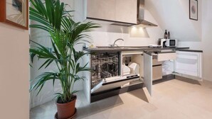 Una cocina moderna con lavavajillas, microondas y una planta en maceta.