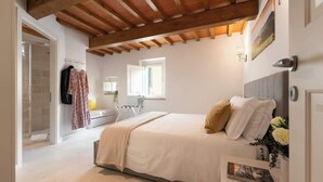 Un dormitorio con cama, ventana, baño y techo de madera.