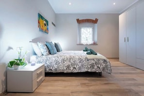 Ein Schlafzimmer mit Bett, Nachttisch und einem Fenster mit Blick.